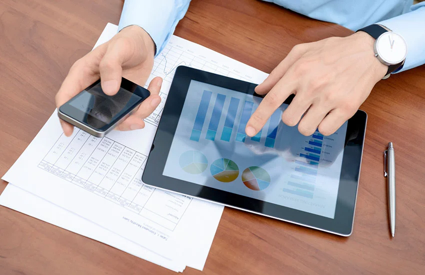 A person in a blue shirt working from his iPhone and iPad.