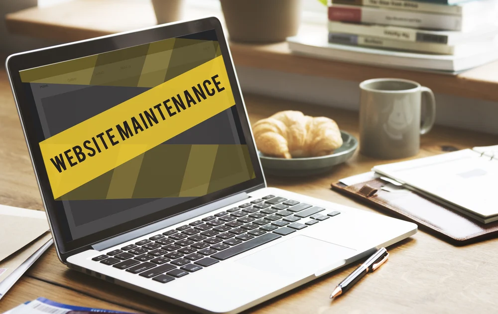 Image of laptop with "website maintenance" in a yellow banner on the screen