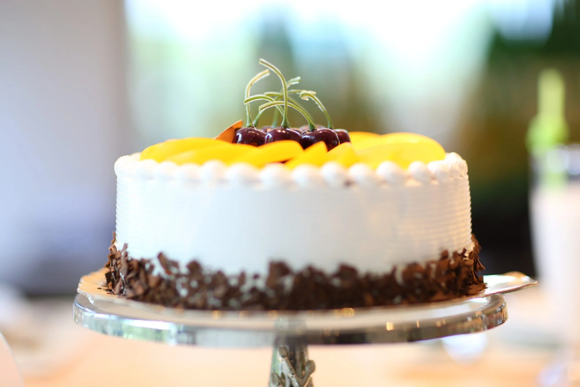 A cake with sliced peaches and cherries on top.