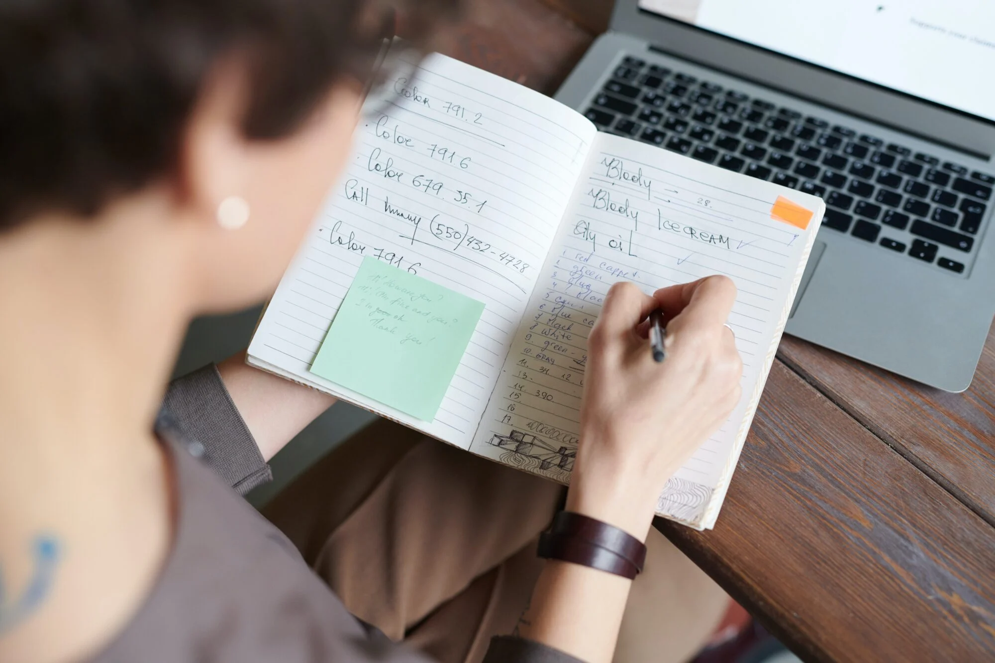 A person holding and writing in a notepad.