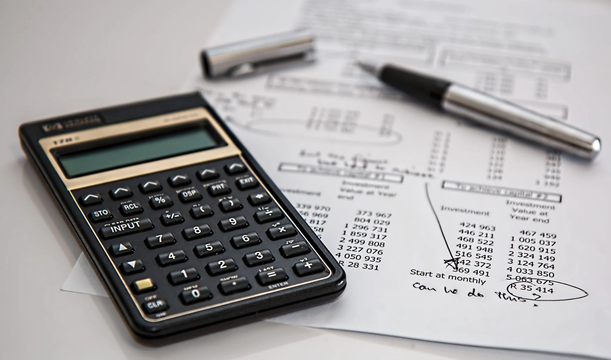 Calculator and pen on printed financial figures for budget planning