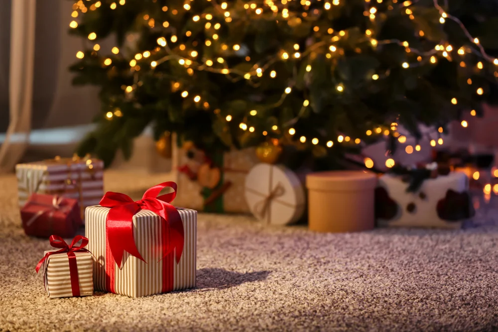 Red and white wrapped christmas gift underneath a christmas tree with beautiful lights