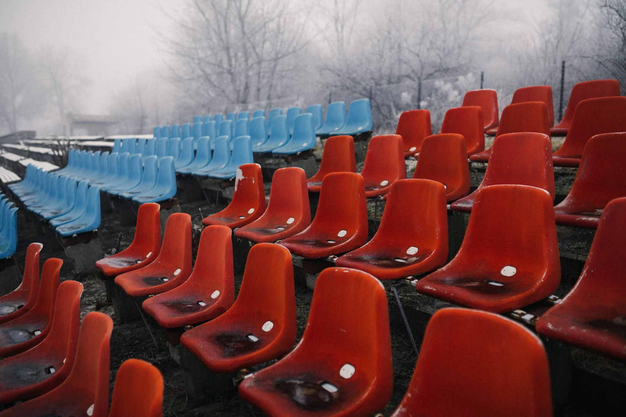 An empty football stadium with blue and red seats displaying scarcity. 