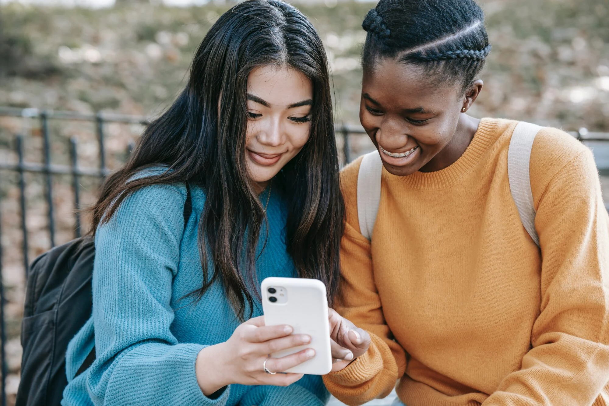 Two friends looking at a social media app on a phone.