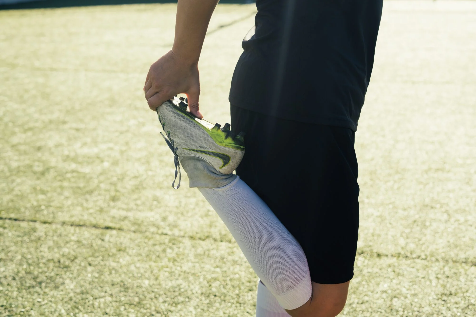 A person wearing Nike shoes while stretching preparing to go on a run.