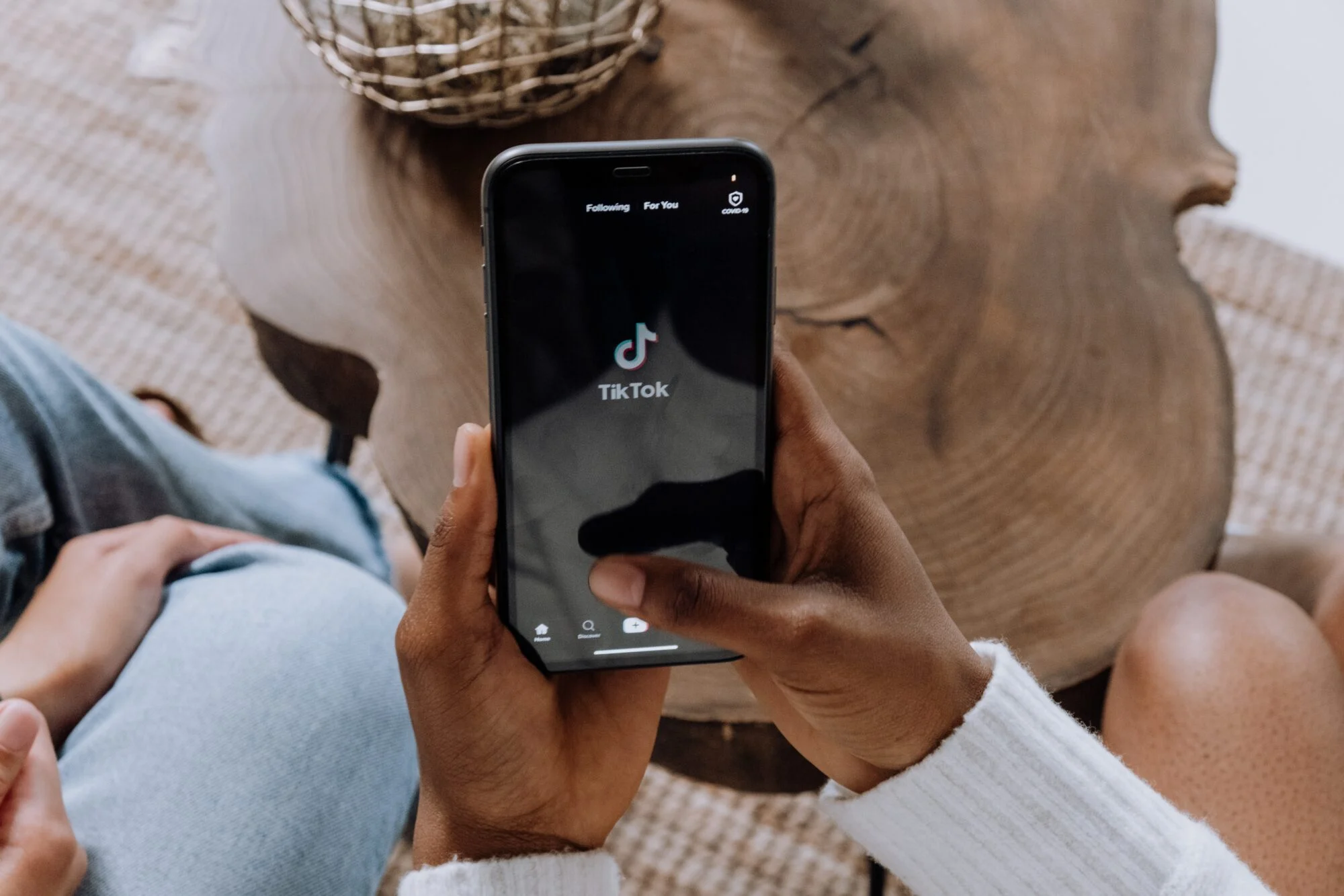 A person using their iPhone to open the TikTok app. 