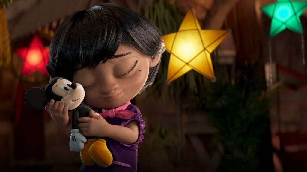 A screenshot of the Disney christmas advert, showing a young girl hugging her Mickey Mouse toy below multicoloured lights.