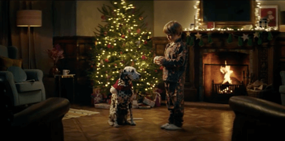 Boy in pyjamas with a Dalmatian beside the tree in Coca-Cola's Christmas advert