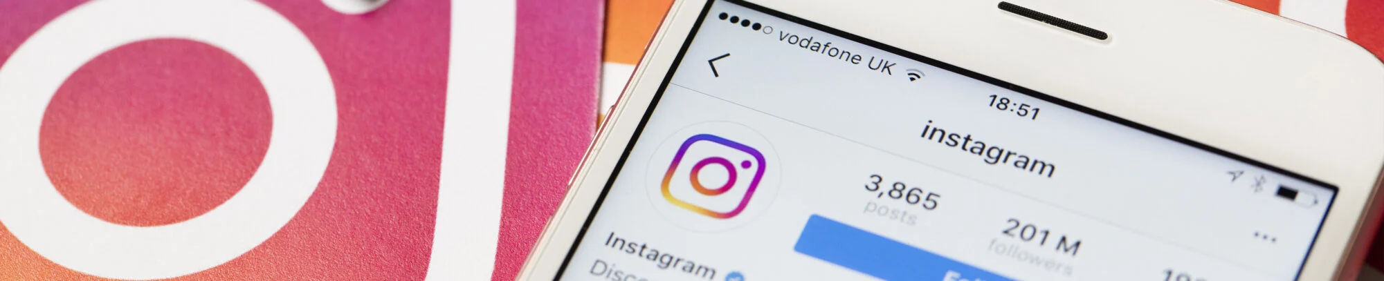 An iPhone with the instagram app open showing the best instagram accounts to follow on a bed of instagram logos.