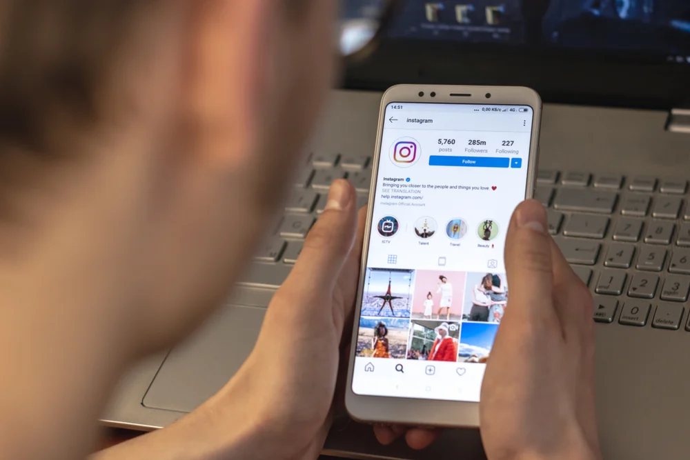 Image of a man looking down at his phone with the best Instagram accounts open