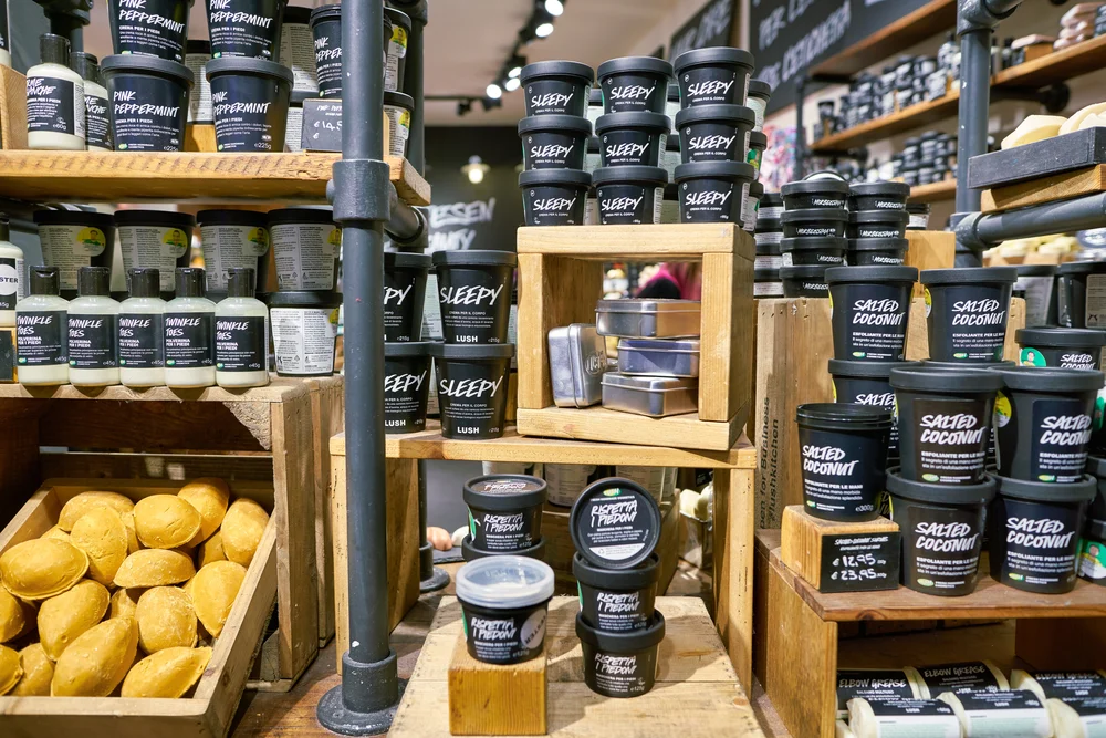 A variety of black pots containing Lush products stacked across various wooden surfaces.