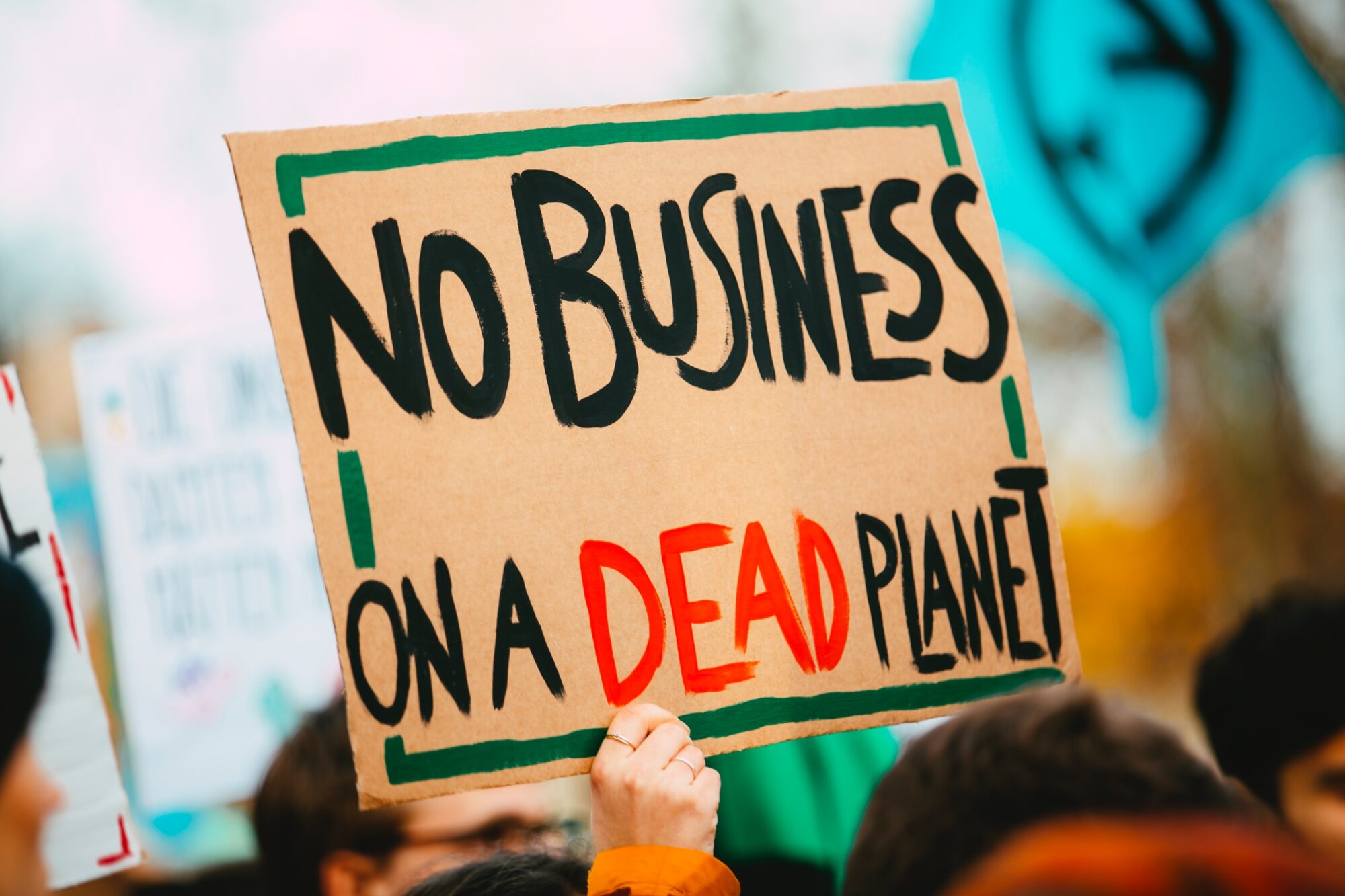 A made up cardboard sign saying no business on a dead planet to showcase environmental marketing.