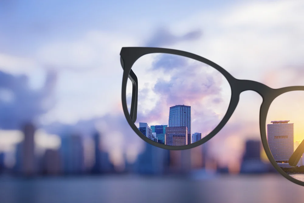 A blurry image overlooking a selection of buildings with a set of glasses in the centre to demonstrate how to increase the resolution of an image without photoshop.