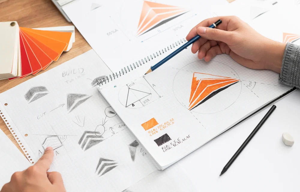 A graphic designer drawing several iterations of a logo to grasp an understanding of their corporate branding. 