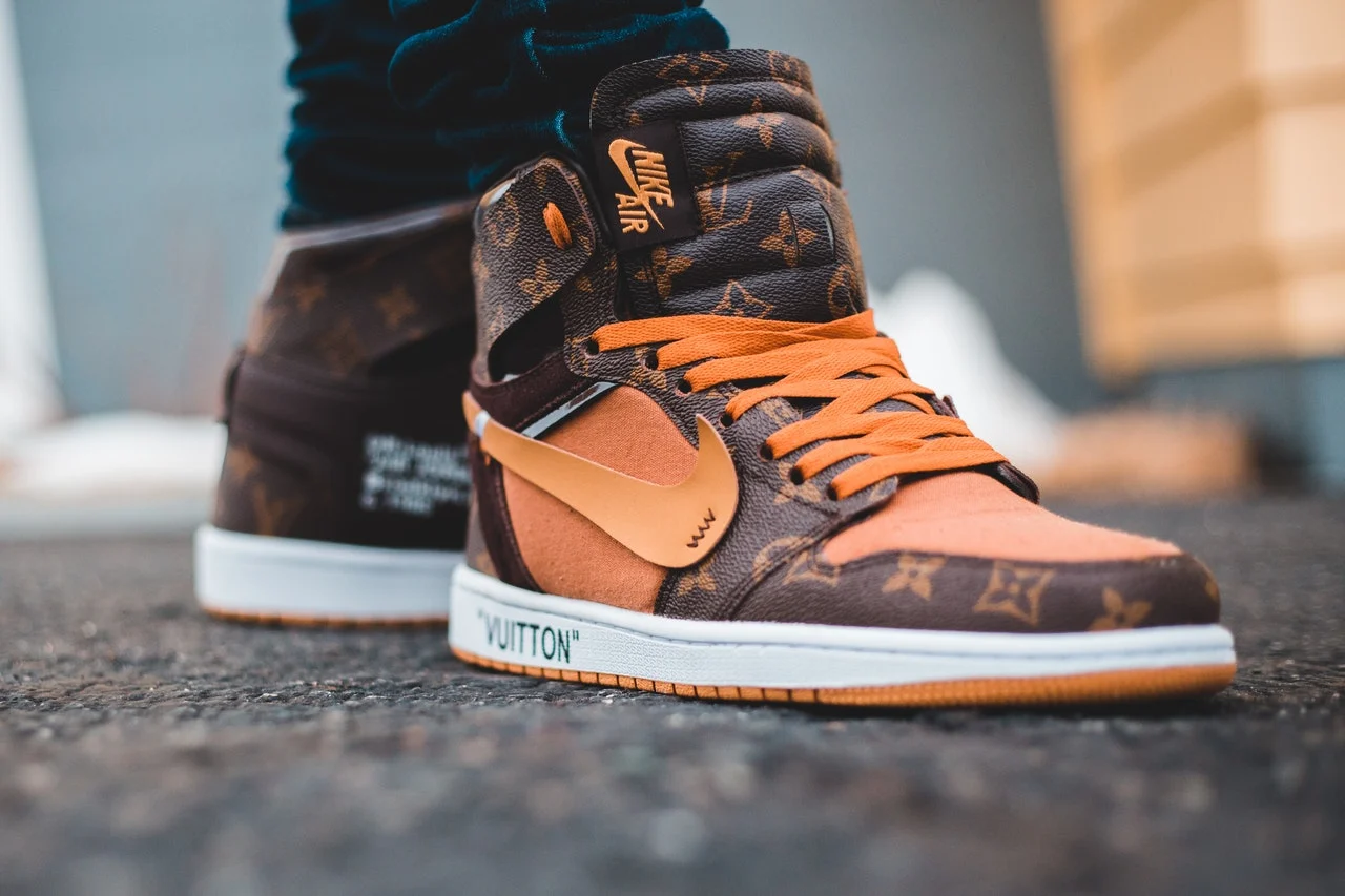 A pair of orange and brown Louis Vuitton Nike shoes.