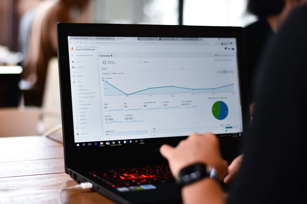 An SEO Executive working on their laptop with Google Analytics open to research how long does SEO take to work. 