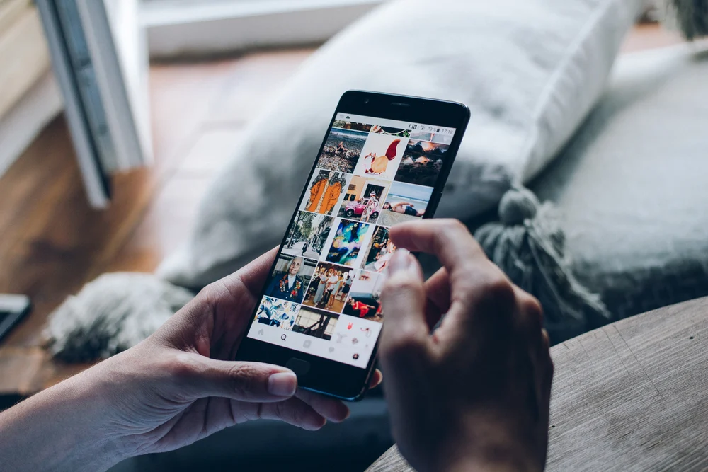 A person scrolling through Instagram on their phone, gaining an understanding on when is the best time to post on Instagram.
