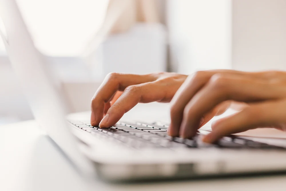 A person typing on their laptop after finding a number of duplicate meta descriptions on their website.