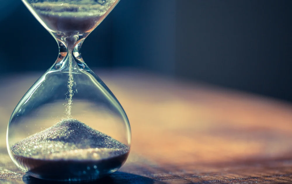 An hourglass on a wooden table to showcase how long does SEO take to work.