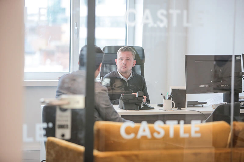 Castle Int. consultant at his desk seen through the agency's branded glass partition
