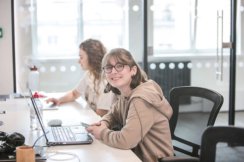 Castle Int. consultant smiling at her desk with her phone in hand