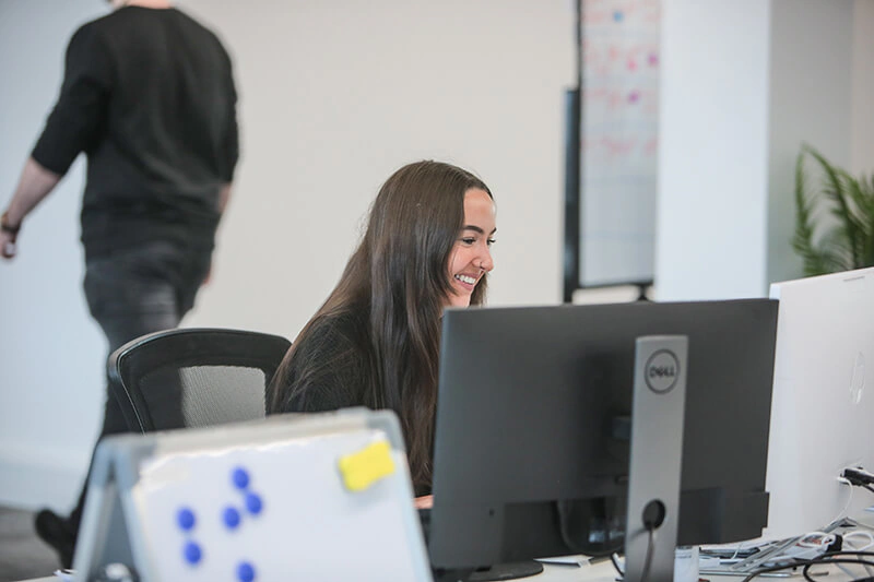 Castle Int. consultant smiling at her monitor in the agency's bright Liverpool office