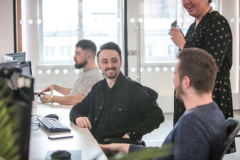 Castle Int. consultant smiling while chatting with colleagues at their desks