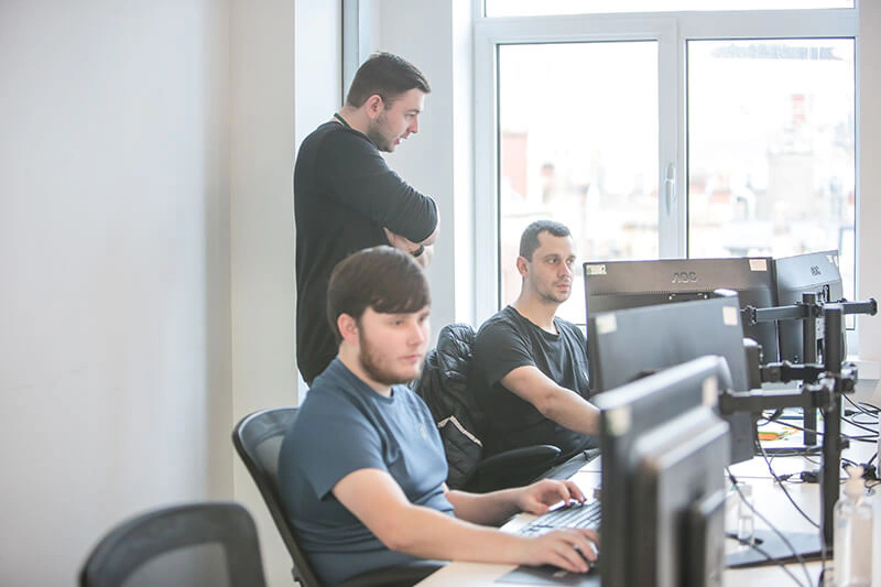 Castle Int. consultants reviewing work together at desks by the office window