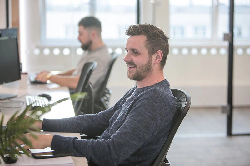 Castle Int. marketing expert smiling at his desk in the Liverpool agency office