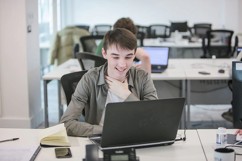 Castle Int. team digital expert smiling while working on a laptop at his desk
