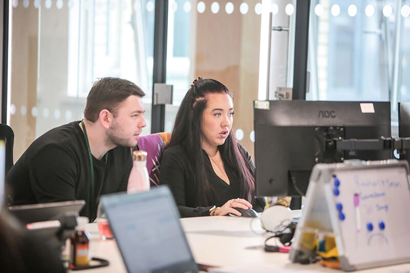 Two Castle Int. colleagues reviewing work together on a monitor in the office