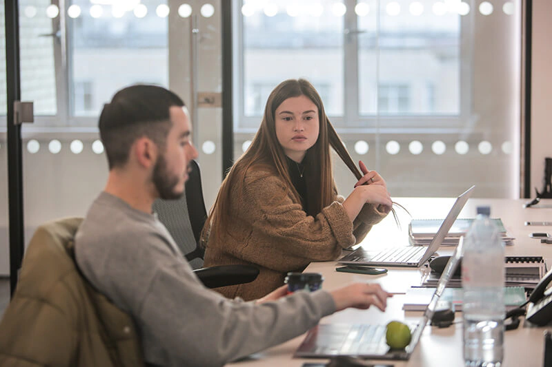 Two Castle Int. consultants in discussion at their desks in the Liverpool office
