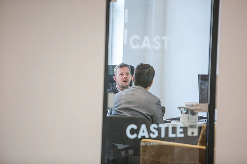Two Castle Int. marketing consultants meeting behind a branded glass door