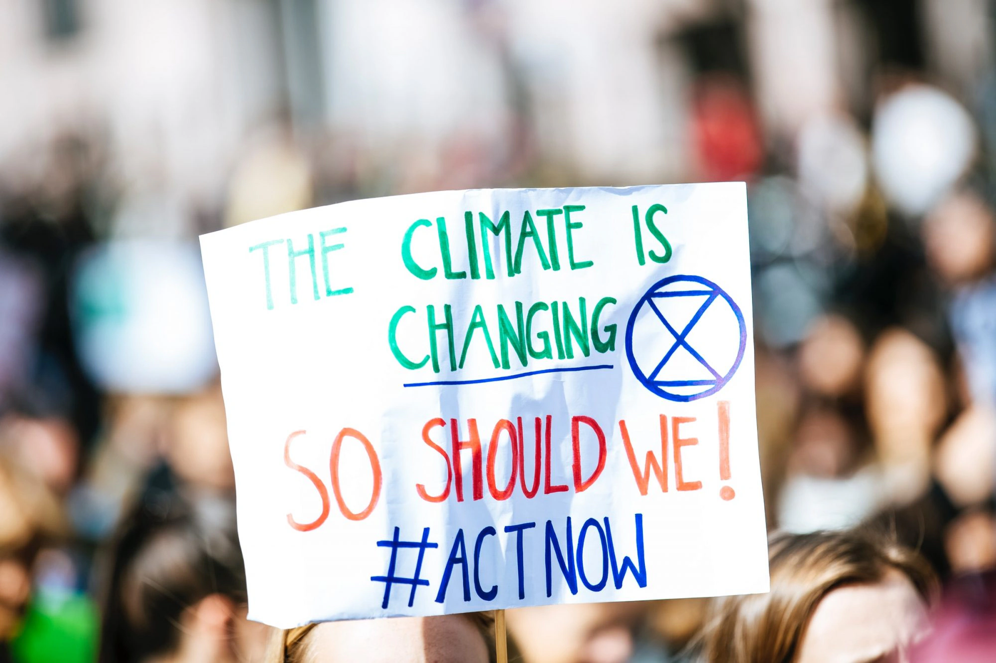 Climate protest placard reading 'The climate is changing, so should we, #ActNow'