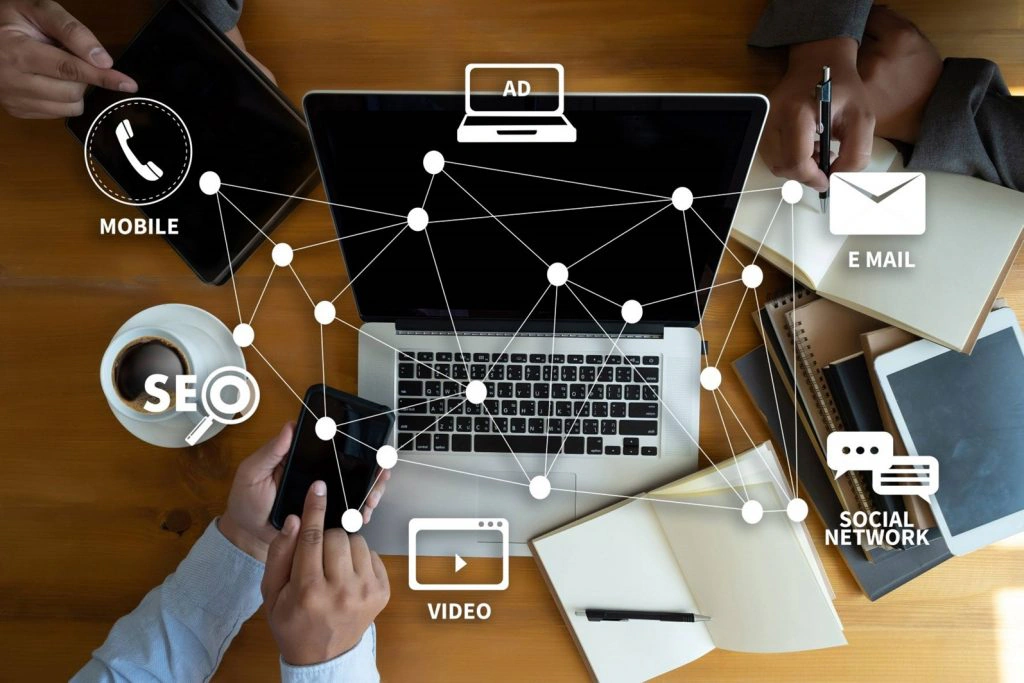 Digital marketing icons for SEO, mobile, email, video and social overlaid on a laptop workspace