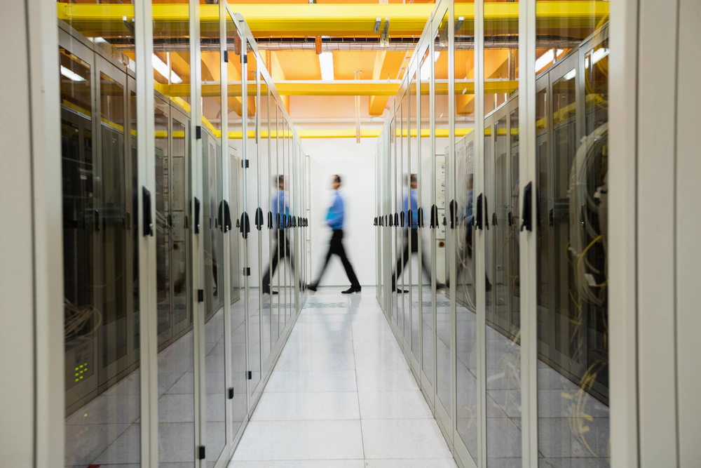 Technician walking through a data centre corridor lined with server cabinets