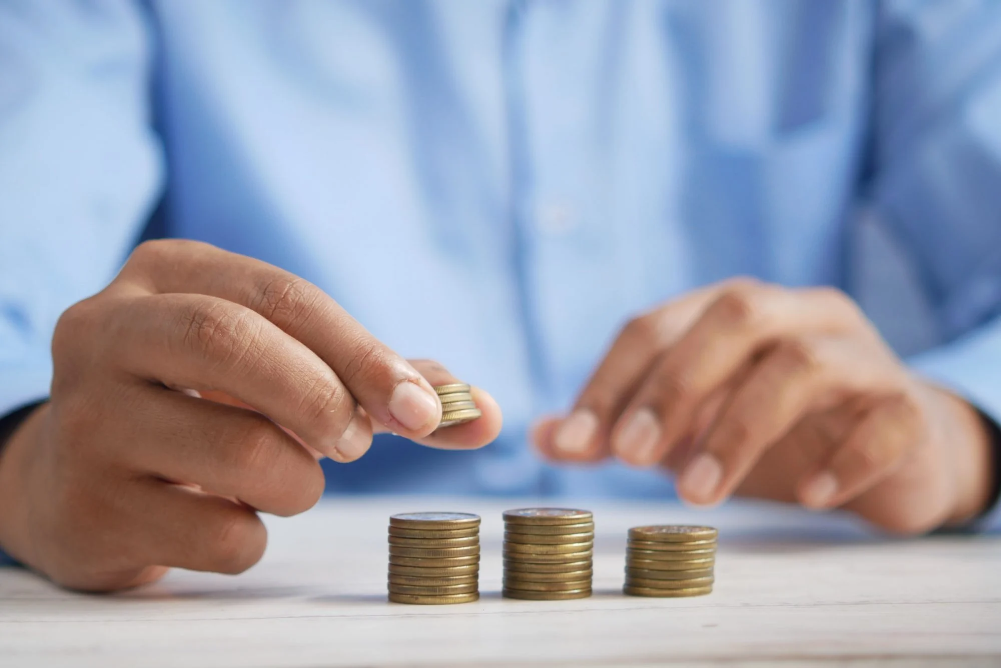Person stacking coins into three piles on a table