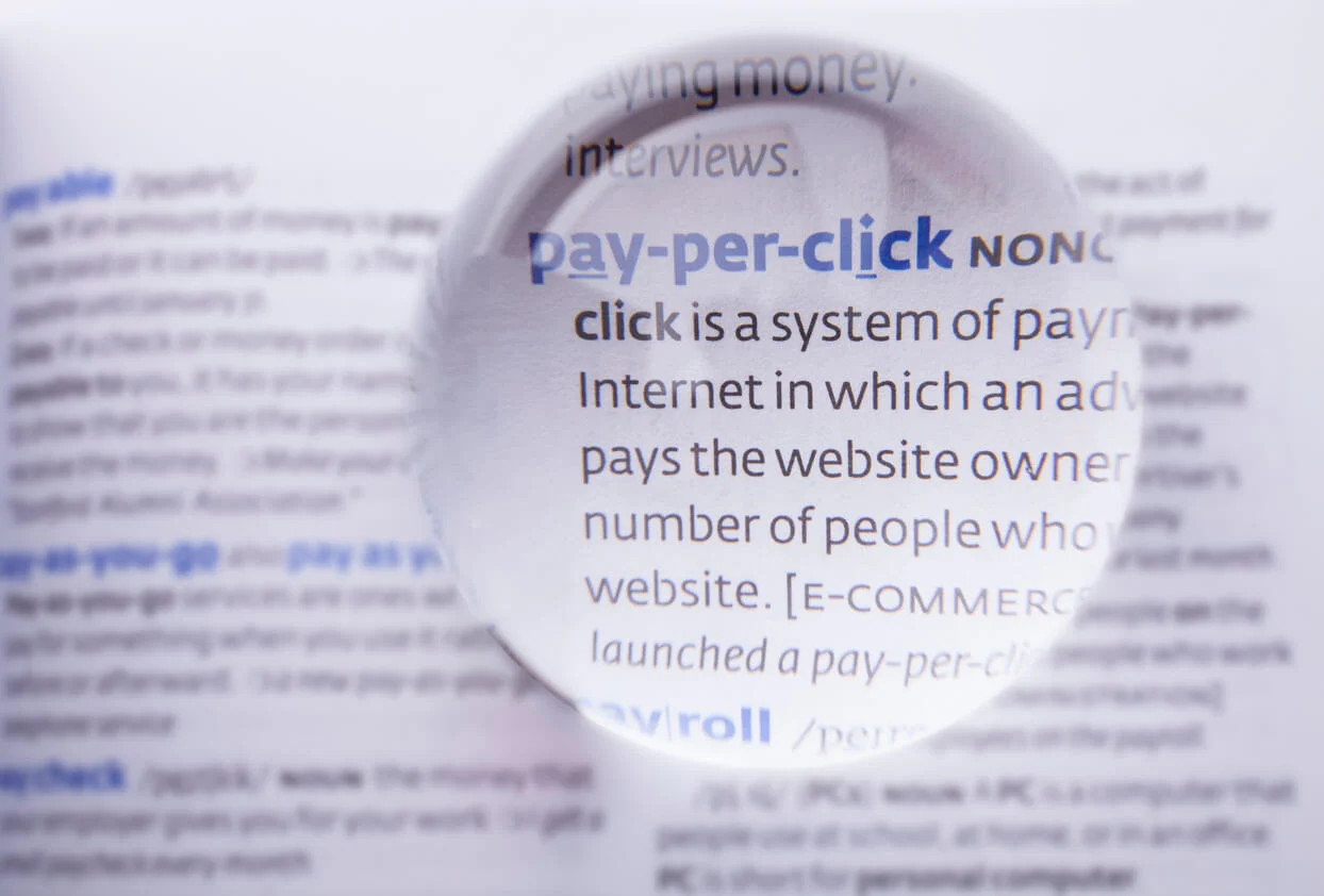 A picture of the dictionary definition of pay-per-click with a magnifying glass magnifying that section.