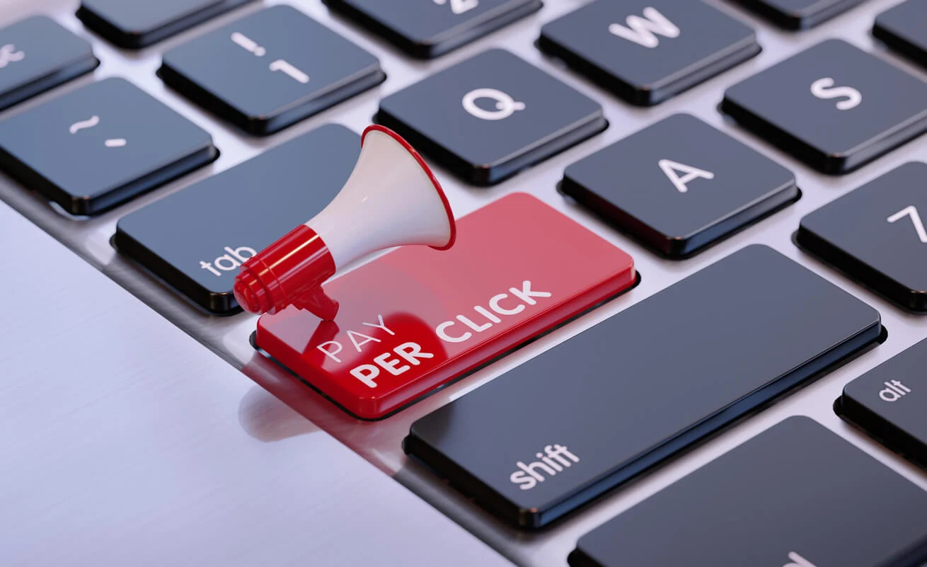 An image of a keyboard with a red key that says 'Pay Per Click' in white writing. Attached to the key is a red and white megaphone.